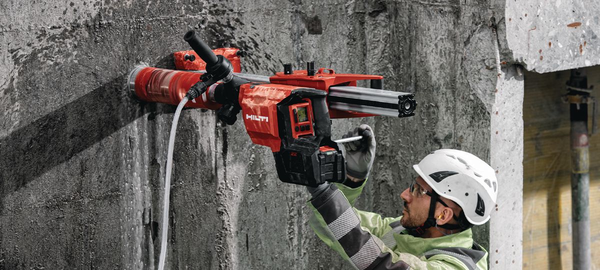 Cropped application picture of the cordless core drill DD 150-U-22 with the SPX A speed core bit and attached to a drill stand. Rig-based wet coring in concrete.