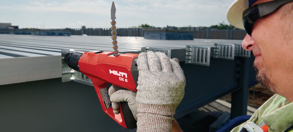 DX 6 with P8 Piston assy, application on a jobsite. Worker in a lift installing deflection clips with X-U 16 pins. (HNA)