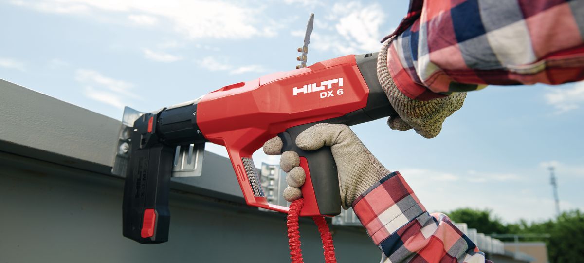 DX 6 MX application on a jobsite. Worker on a lift installing deflection clips with X-U 16 pins using a tether. (HNA)