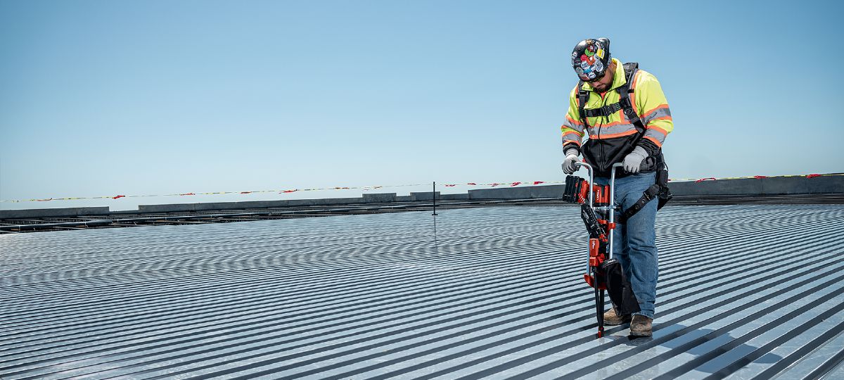 Cropped application image of a worker installing screws on a metal roof deck, using the Nuron ST 2000-22 and SDT 9. Produced by HNA, April 2024, Dallas, TX. 