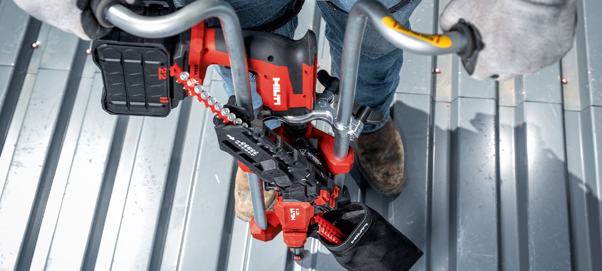 Cropped application image of a worker installing screws on a metal roof deck, using the Nuron ST 2000-22 and SDT 9. Produced by HNA, April 2024, Dallas, TX. 