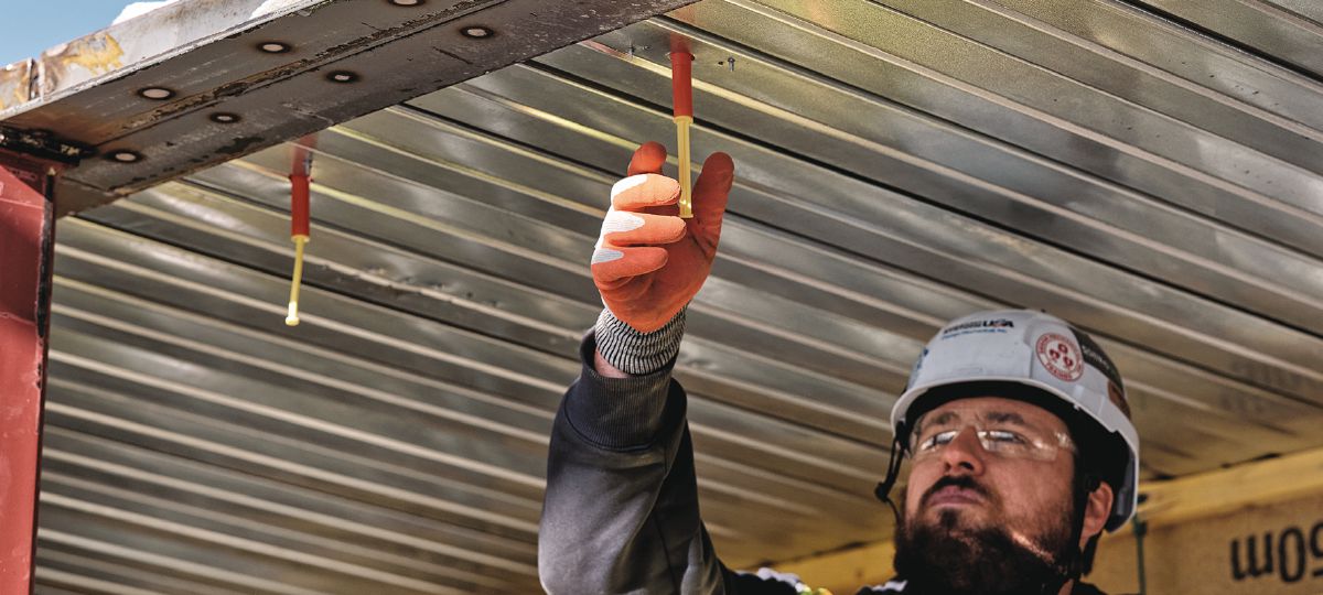 Cropped application image of Construction worker installing threaded rod into KCCM-MD push-to-connect anchors on a metal deck. Golden, CO. 2024.