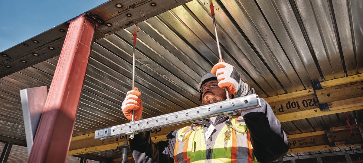Cropped application image of Construction worker installing threaded rod into KCCM-MD push-to-connect anchors on a metal deck. Golden, CO. 2024.