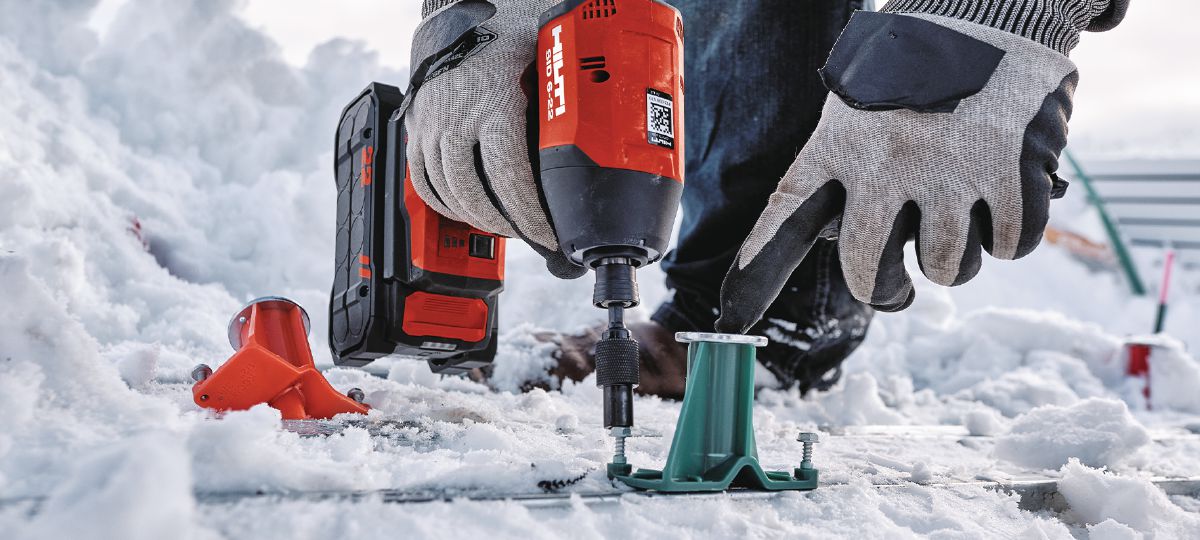 Cropped application image of Construction worker using an SID 6-22 + KCM-MD Kwik Cast combo bit to install KCCM-MD S anchors on a snowy metal deck jobsite. Golden, CO. 2024.
