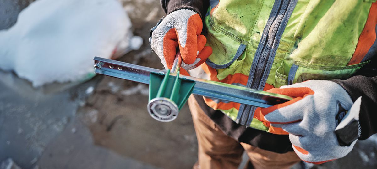 Cropped application image of Construction worker holding KCCM-MD L Kwik Cast Connect (multi-thread) cast-in-place anchor on a metal deck jobsite. Golden, CO. 2024.